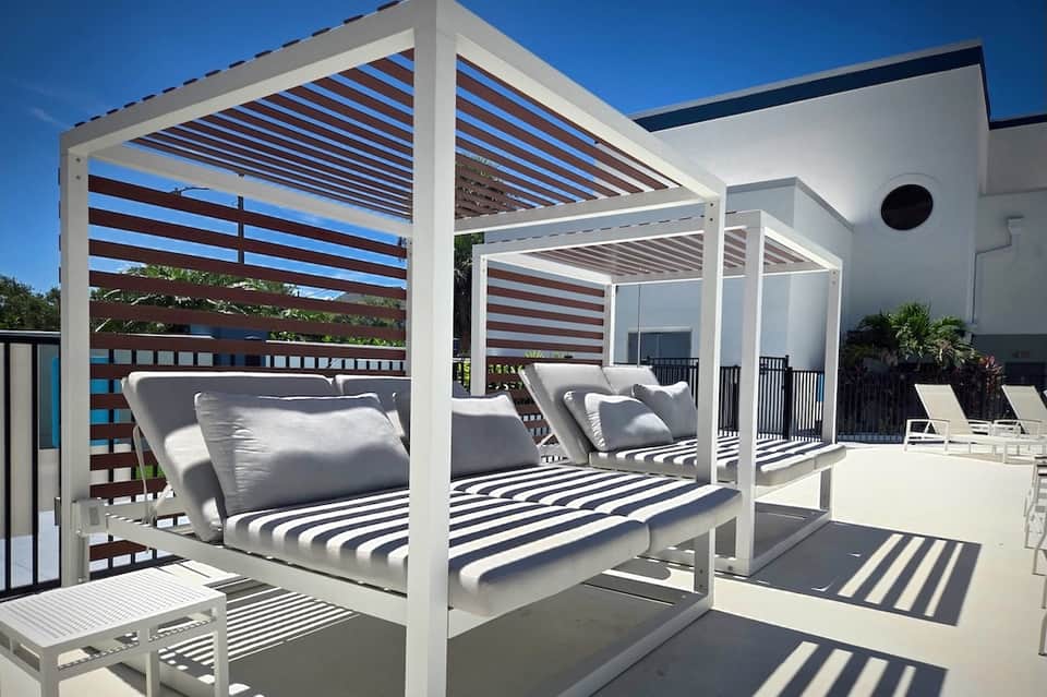 Outdoor cabana beds with striped awnings and lounge chairs in sunlight