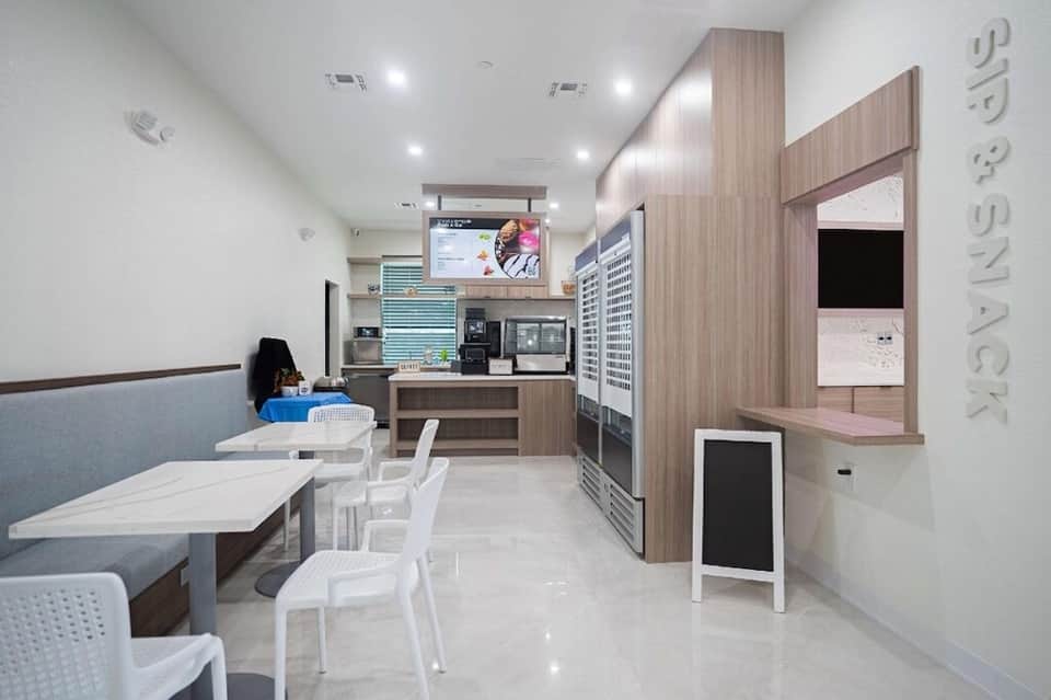 Modern casual dining area with white furniture, wooden cabinetry, and open kitchen concept
