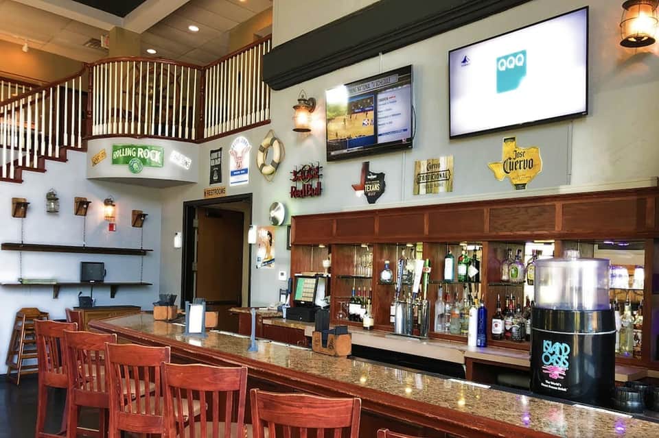 Hotel bar interior with wood furnishings, neon signage, flat-screen TV, and liquor display