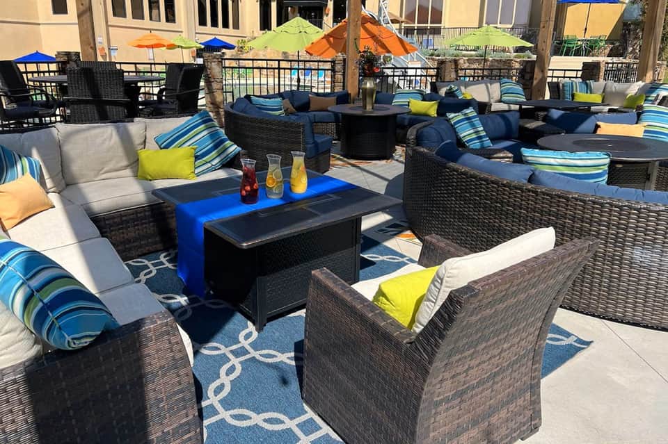 Waterfront patio lounge with navy furniture, striped cushions, colorful umbrellas, and ocean view
