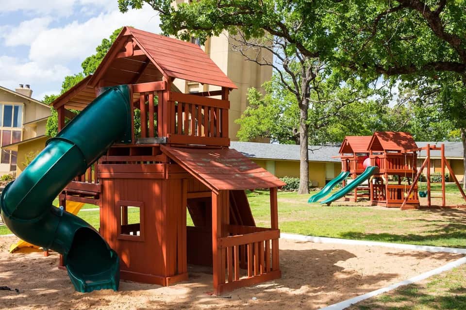 Children's playground with red wooden play structures and slides on grass