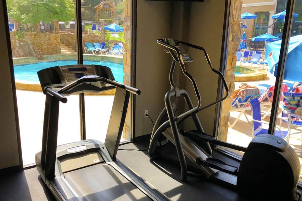 Fitness center with treadmills and exercise equipment overlooking resort pool