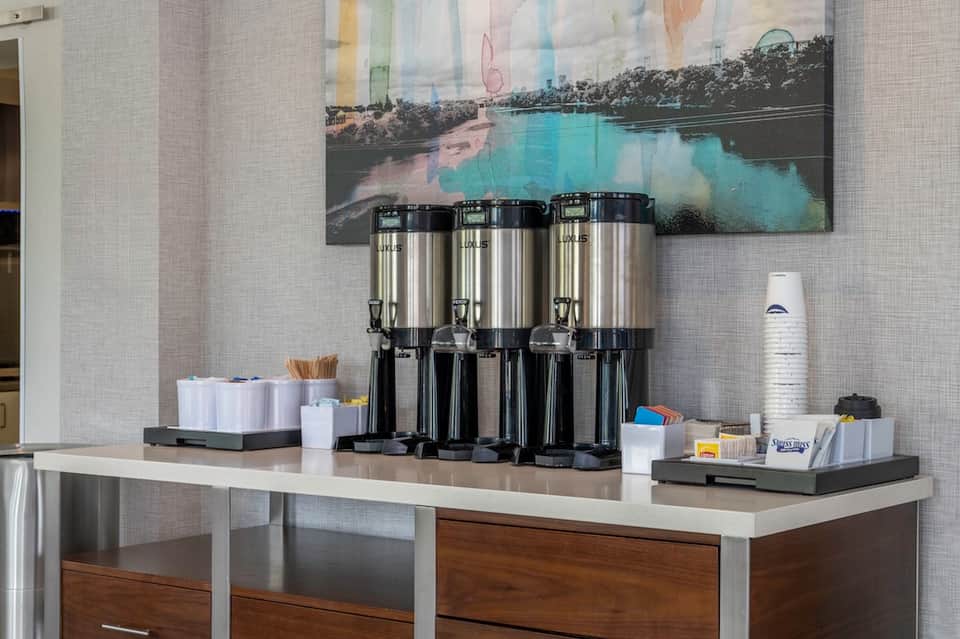 Coffee station with three thermal dispensers and hospitality supplies on counter