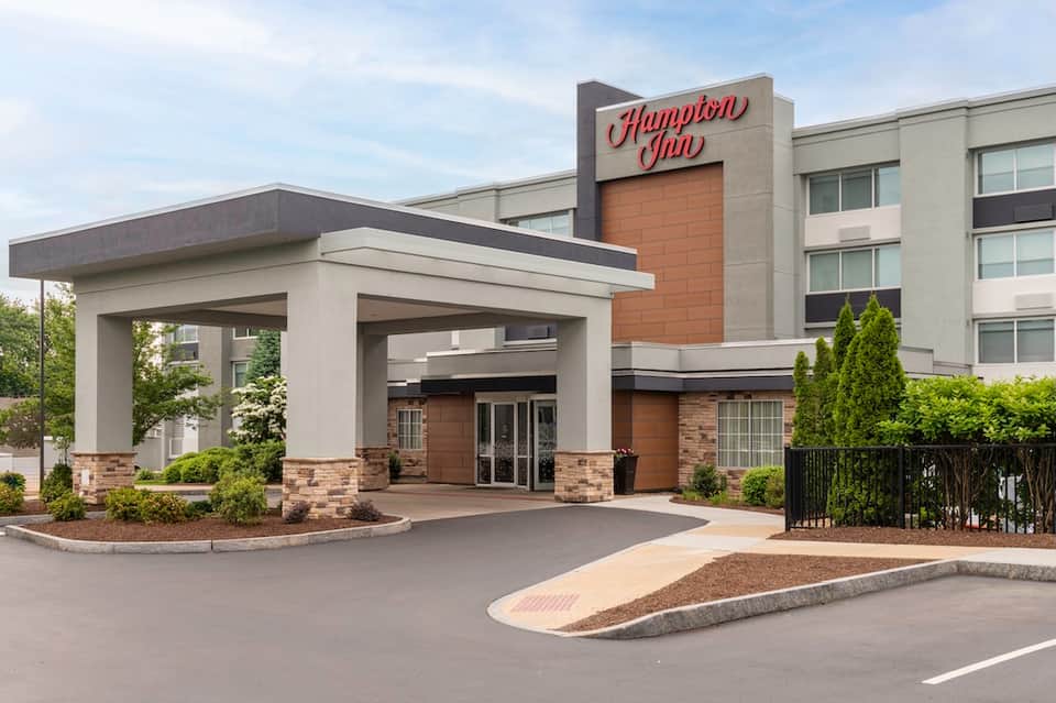 Hampton Inn hotel exterior with modern porte-cochere entrance and multi-story brick and stone façade