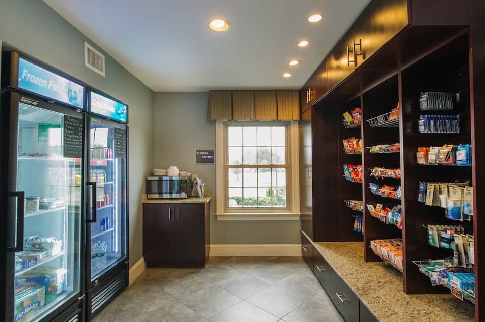 Hotel convenience store with refrigerated section, snack shelves, window view, and modern interior design