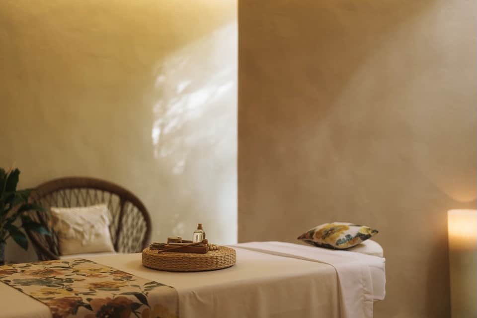 Minimalist spa room with woven round table, modern chair, and natural sunlight on white walls