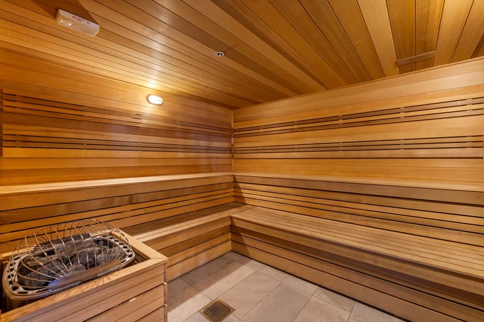 Wooden sauna interior with tiered benches and warm cedar paneling throughout