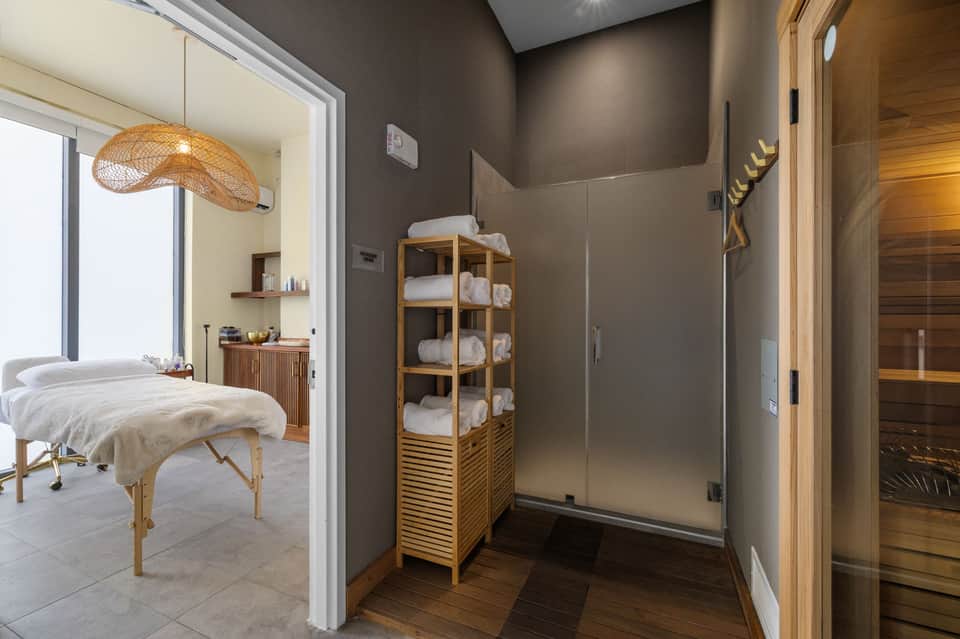 Spa bathroom with wooden sauna, rain shower, massage table, and amenities shelf