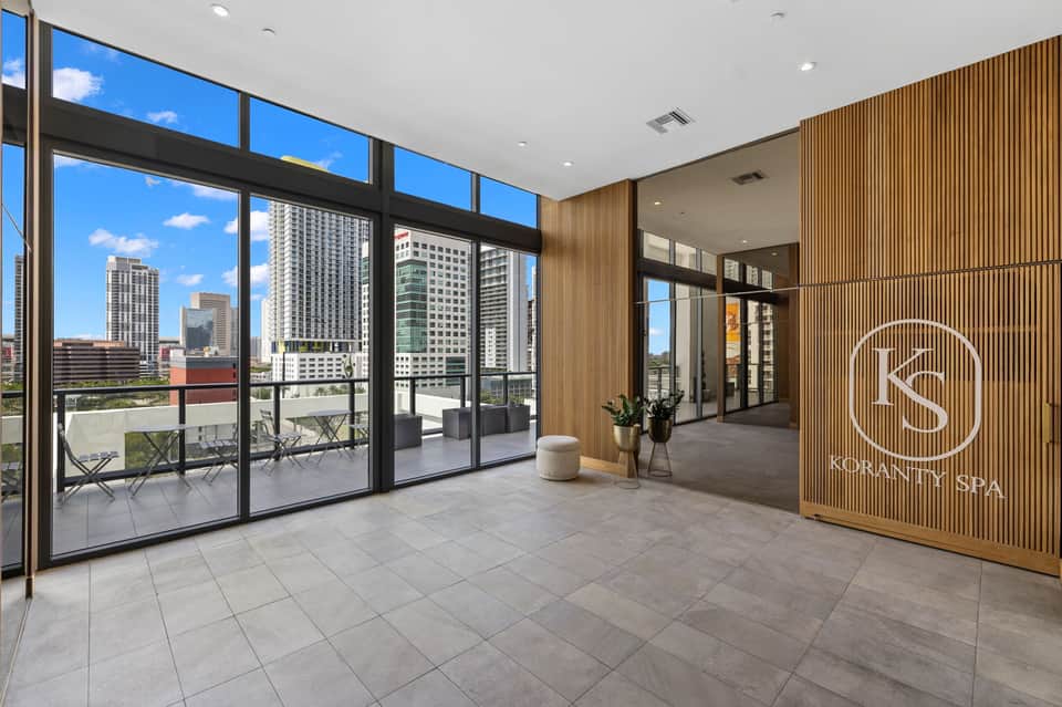 Urban spa entrance with city skyline views through floor-to-ceiling windows and modern wood paneling