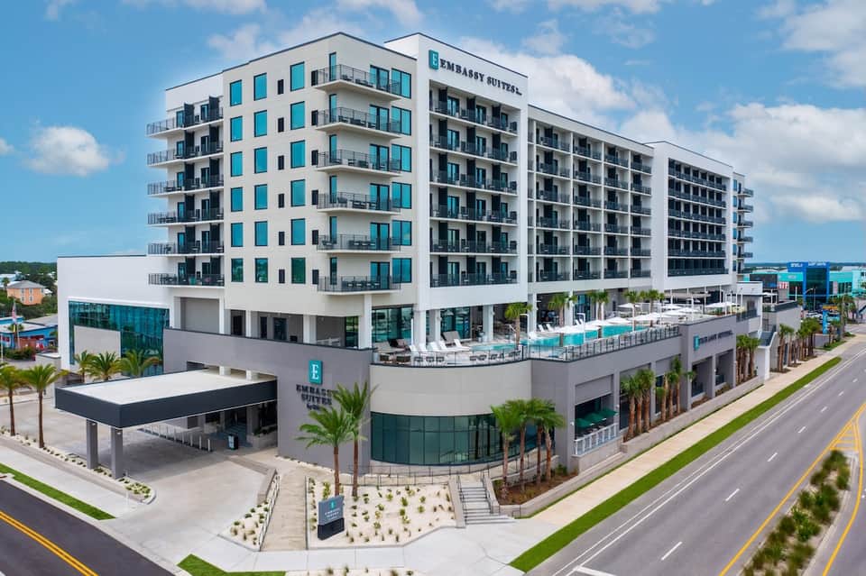Modern beachfront resort building with turquoise accents, balconies, and ground-level pool area