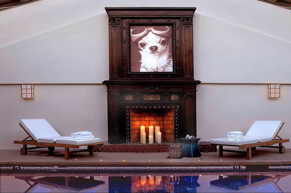 Luxury spa fireplace lounge with wooden loungers, white towels, ornate dark mantel, and lit candles