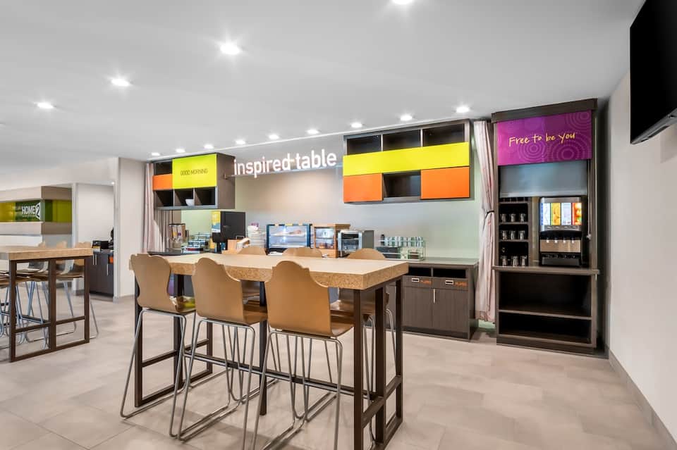 Modern hotel lobby with colorful signage, bar seating, and bright contemporary design elements