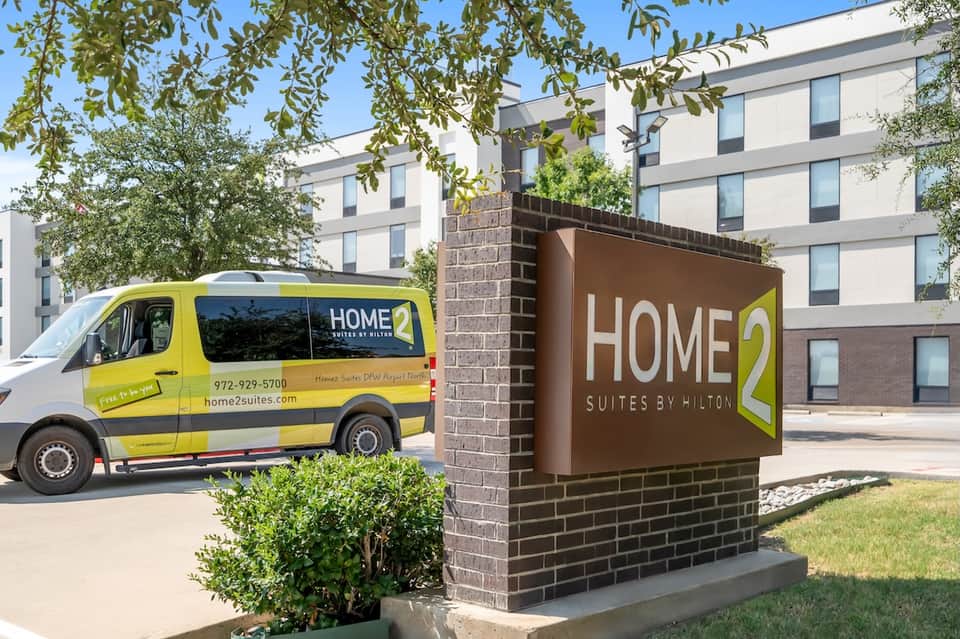 Home2 Suites by Hilton hotel exterior with yellow service vehicle and multi-story modern building