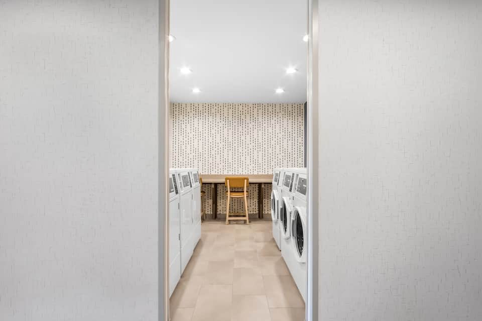 Modern laundry facility with white washers and dryers along cream-colored walls