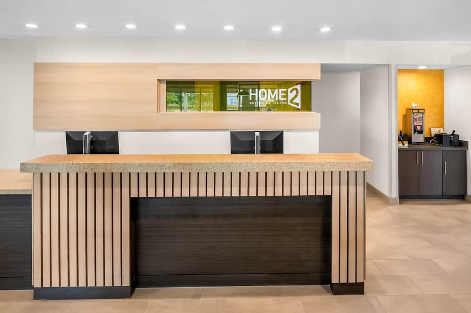 Modern hotel lobby reception desk with wood paneling and Home2 branding