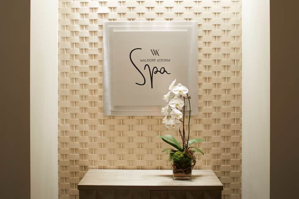 Waldorf Astoria Spa entrance sign with white orchid flower on textured wall
