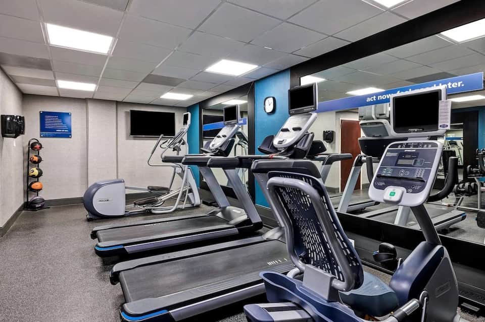 Fitness center with treadmills, exercise equipment, and blue accent wall accents