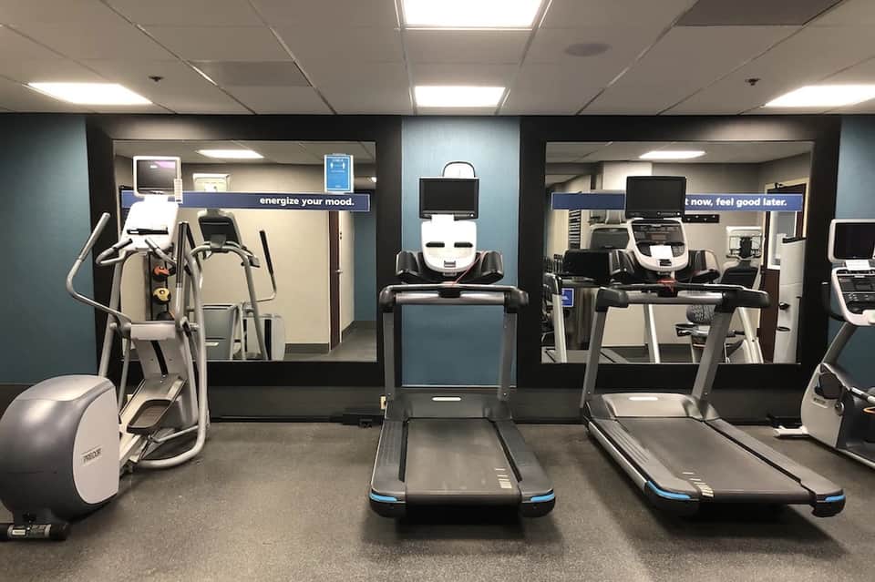 Bright fitness center with cardio equipment, treadmills, ellipticals, and motivational wall signage