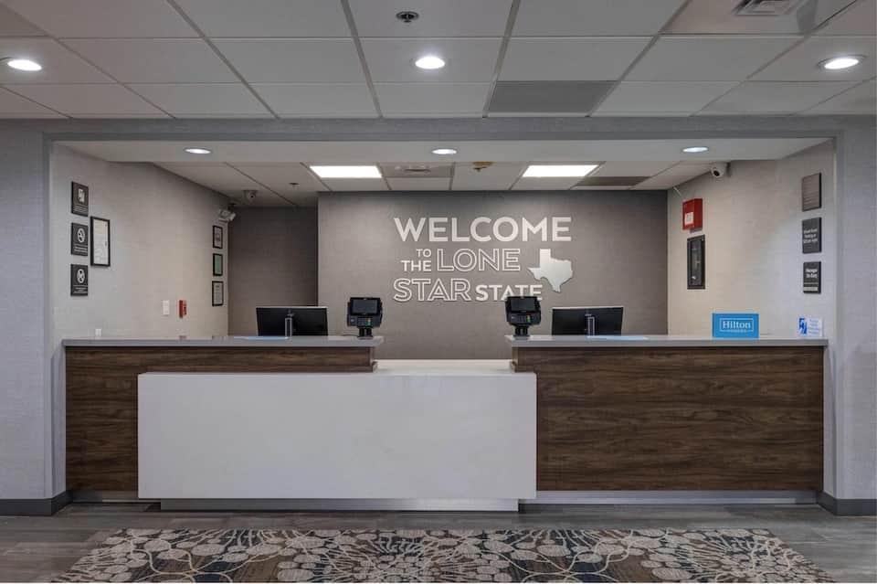 Hotel check-in desk with 'Welcome to the Lone Star State' Texas-themed wall signage