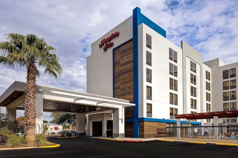 Modern Hampton Inn hotel entrance with blue accents, palm tree, and contemporary architecture