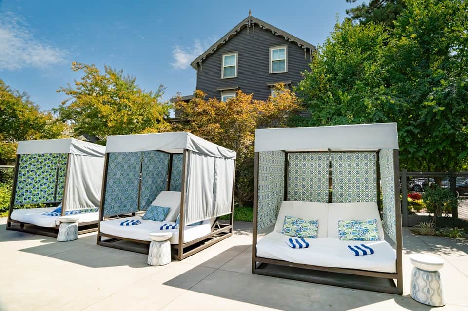 Outdoor spa area with two white canopy daybeds with blue patterned cushions near historic building