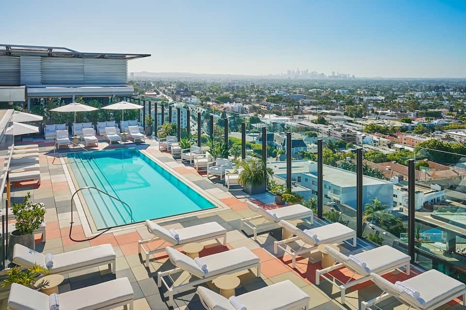 Rooftop pool overlooking sprawling cityscape with mountains in distance