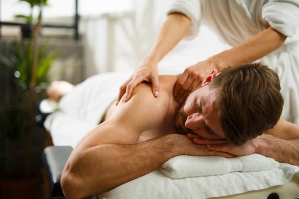 Massage therapist performing a back massage on a male client in a spa setting