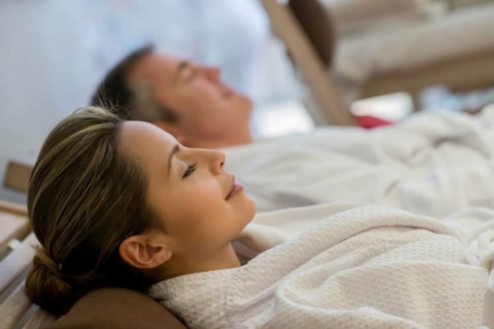 Two guests relaxing on spa beds in white linens at resort wellness center