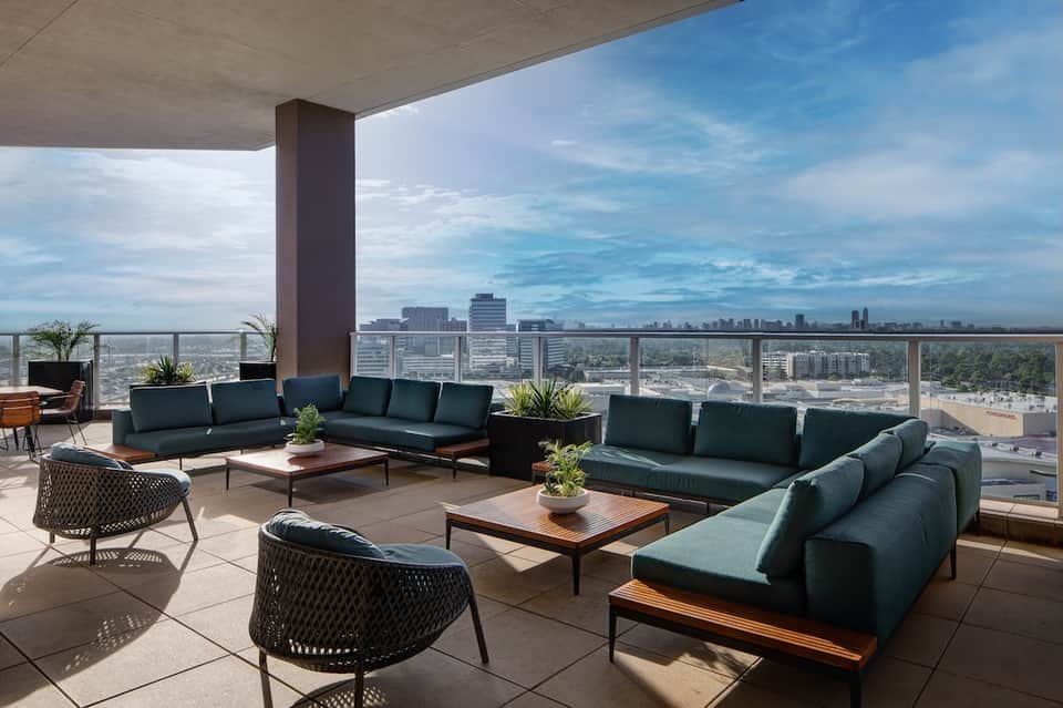High-rise hotel terrace with modern green seating, city skyline views, and contemporary furnishings