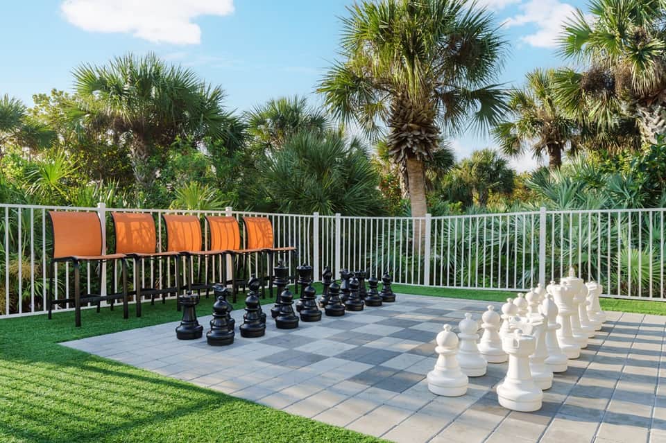 Outdoor recreation area with giant chess game, palm trees, and seating