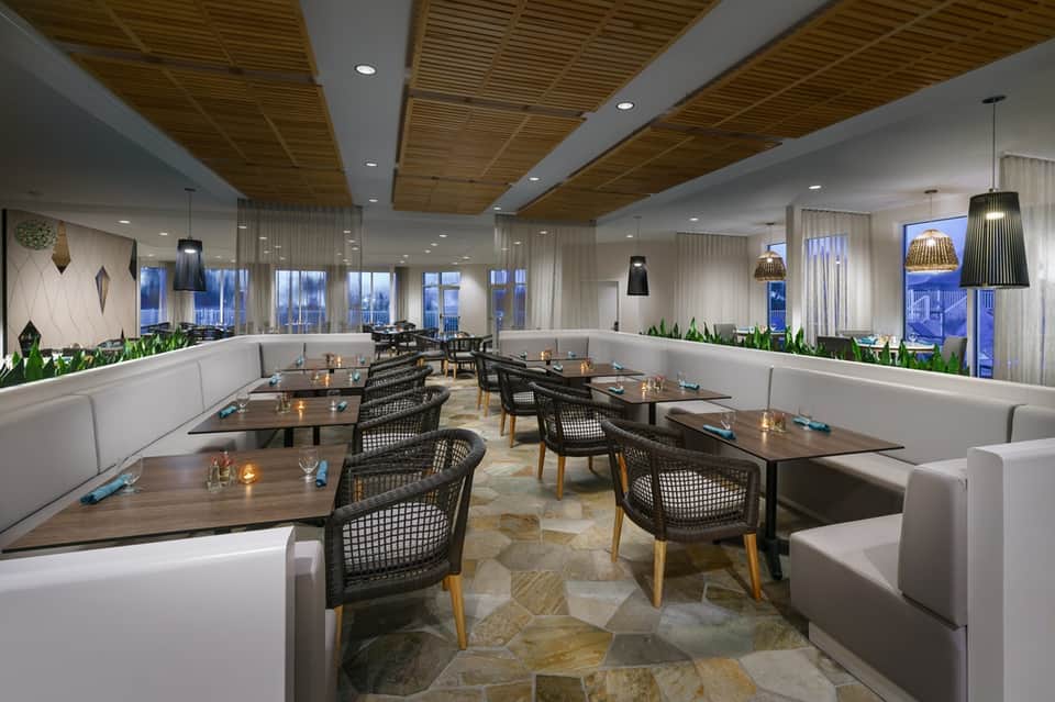 Contemporary rooftop restaurant with wooden ceiling, floor-to-ceiling windows, and city views