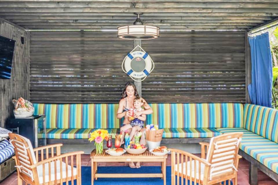 Woman with child in striped boathouse lounge with nautical decor and life preserver on wall