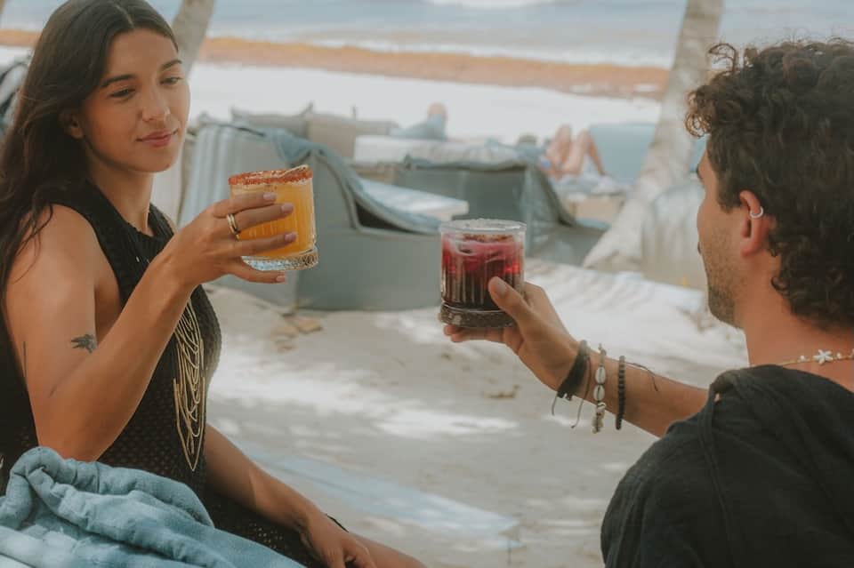 Couple toasting with cocktails on a rooftop deck overlooking a coastal harbor and boats