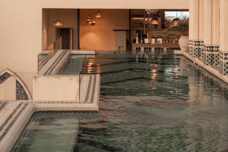 Luxurious indoor thermal pool with geometric tile details, spa lighting, and warm ambient glow