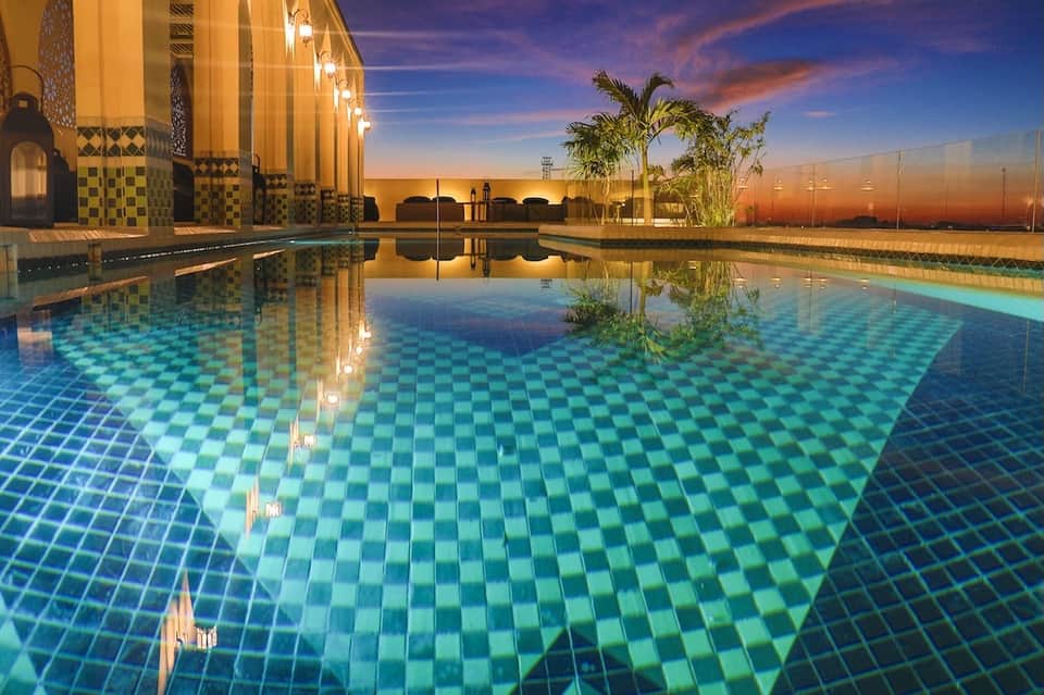 Outdoor pool at dusk with ornate building reflected in water