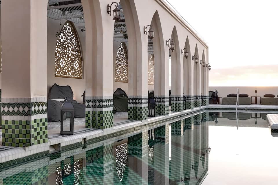 Ornate indoor spa pool with Moroccan tile work, arches, and decorative lanterns