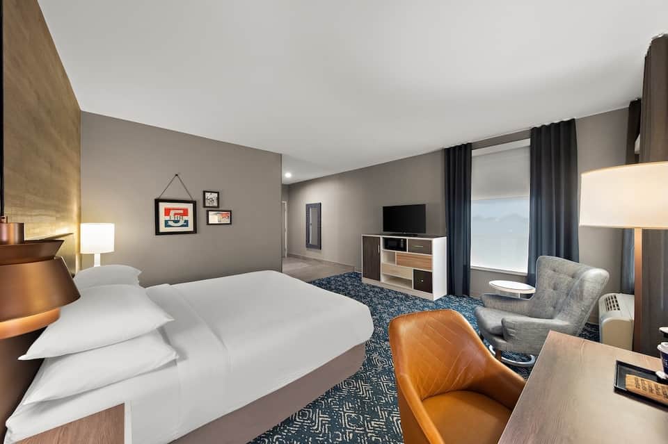 Spacious hotel bedroom with queen bed, flat-screen TV, and contemporary furnishings
