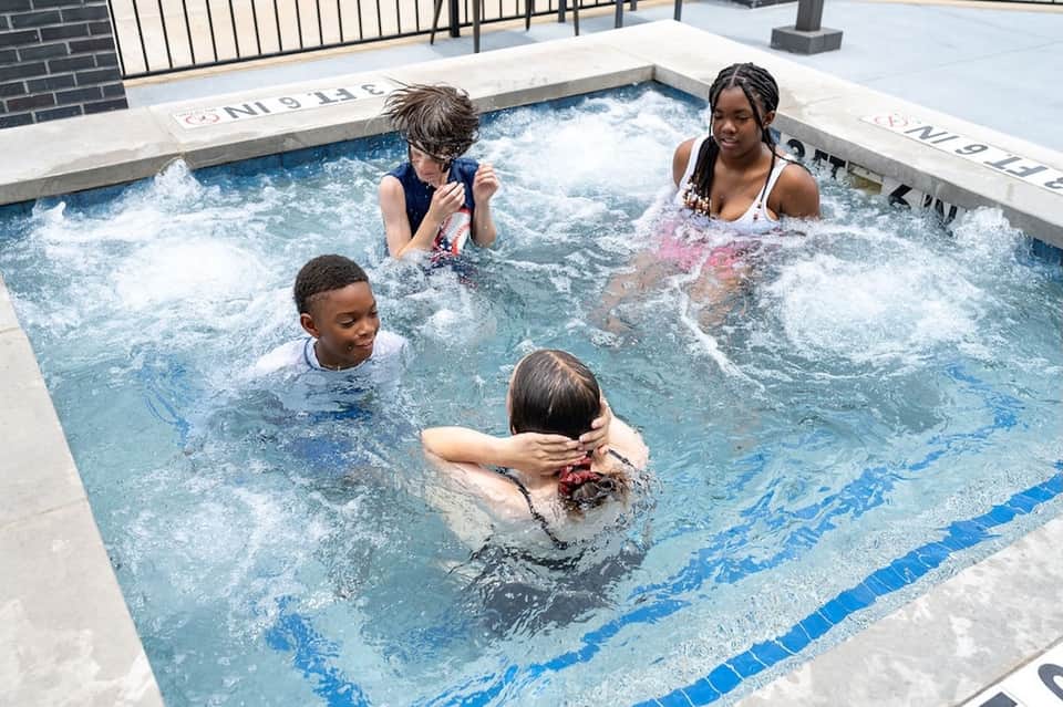 Children enjoying a hot tub with jets and bubbling water on rooftop deck