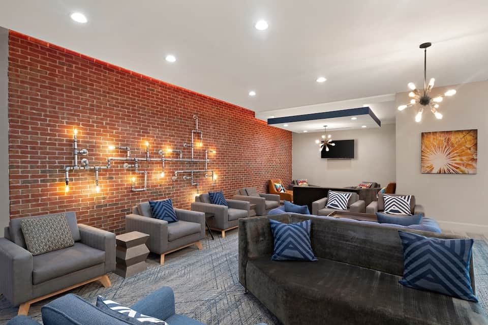 Lounge room with gray couches, red brick accent wall, and decorative lighting