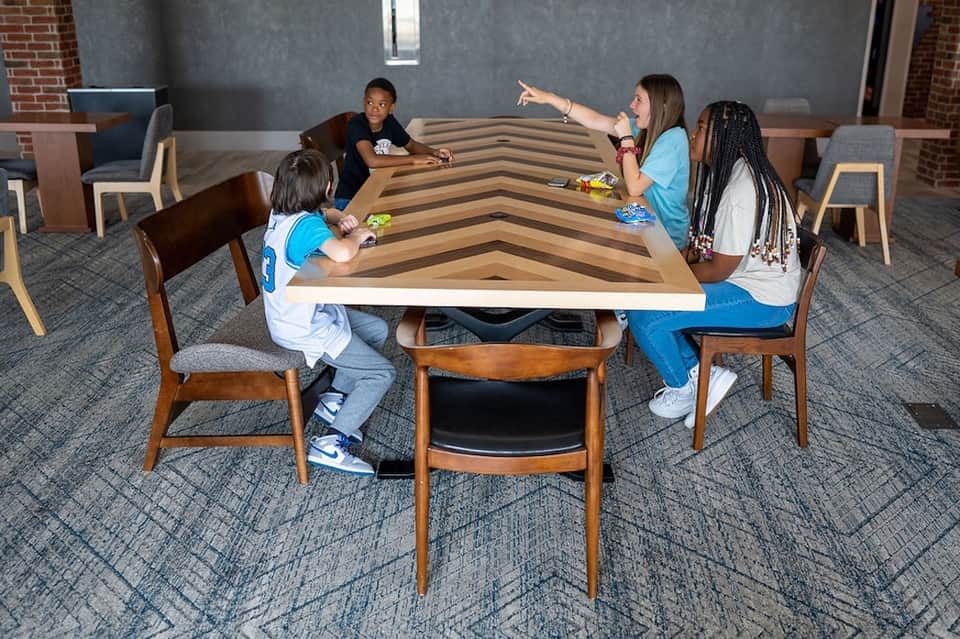 Children playing at a wooden game table in a modern hotel common area