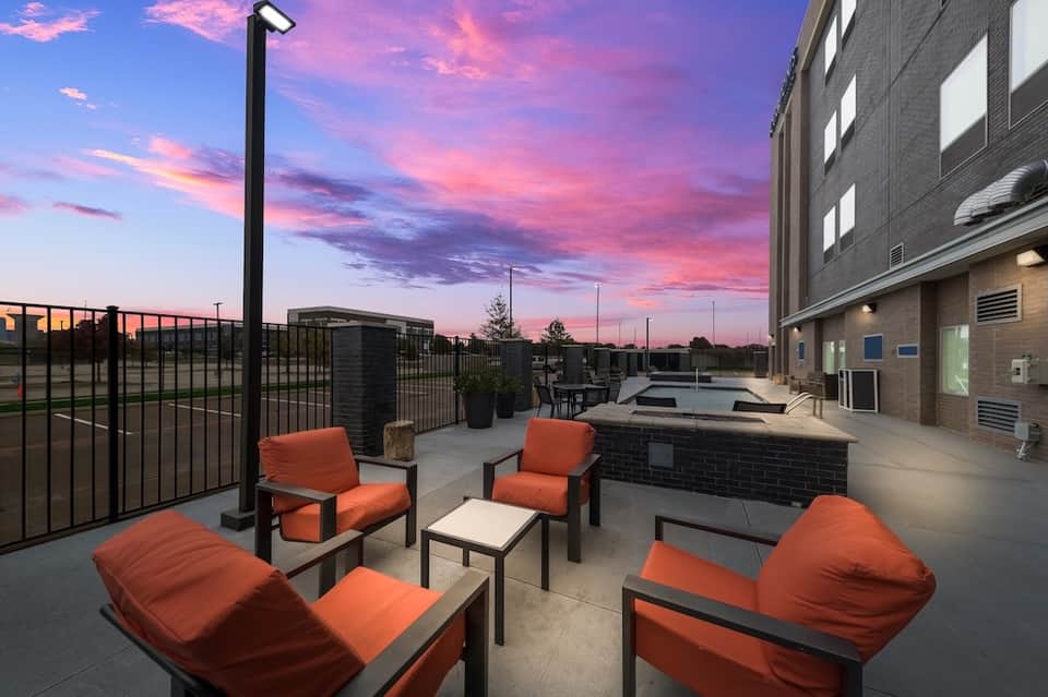 Rooftop patio with orange seating, fire pit, and sunset sky at dusk