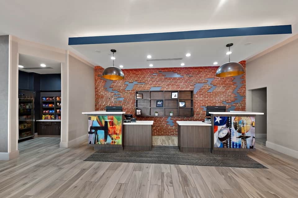 Modern hotel check-in area with brick wall, steel pendant lights, and contemporary desk design