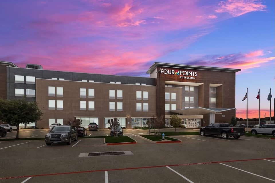 Four Points by Sheraton hotel exterior at dusk with dramatic pink and purple sky