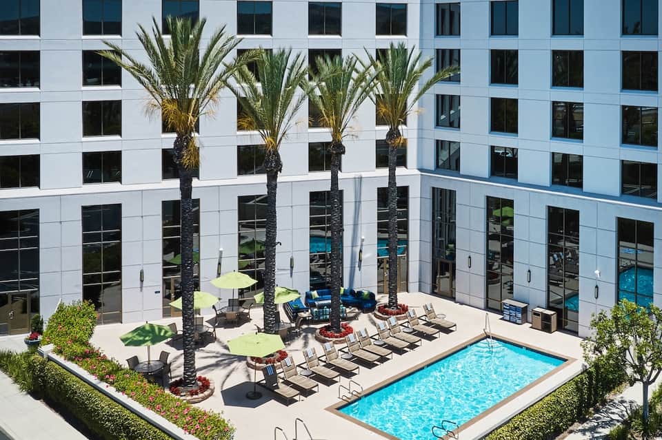Courtyard pool surrounded by modern white buildings with palm trees and lounge chairs
