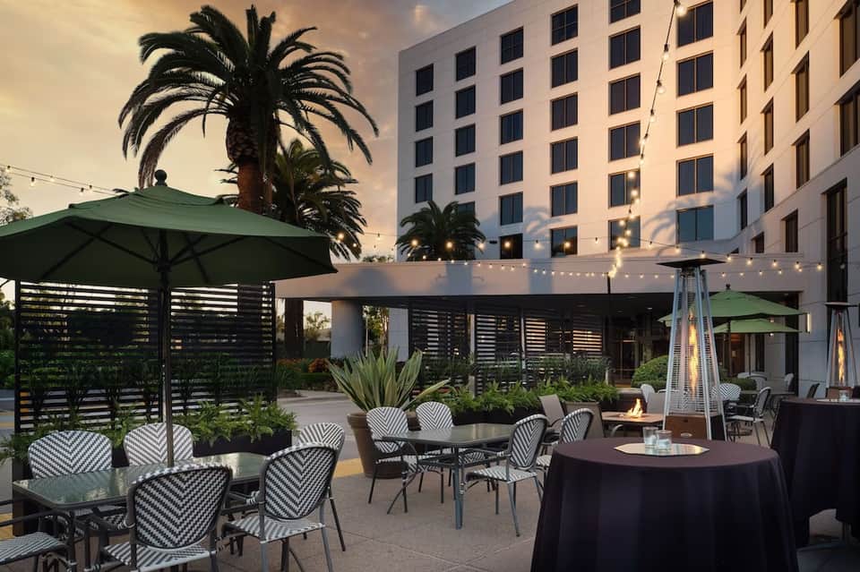 Modern rooftop patio with green umbrellas, striped chairs, and downtown building backdrop at dusk