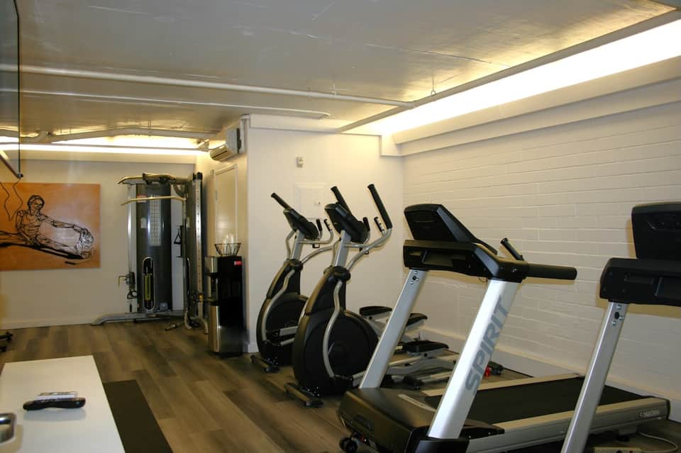 Modern fitness center with treadmills, exercise equipment, and white brick walls