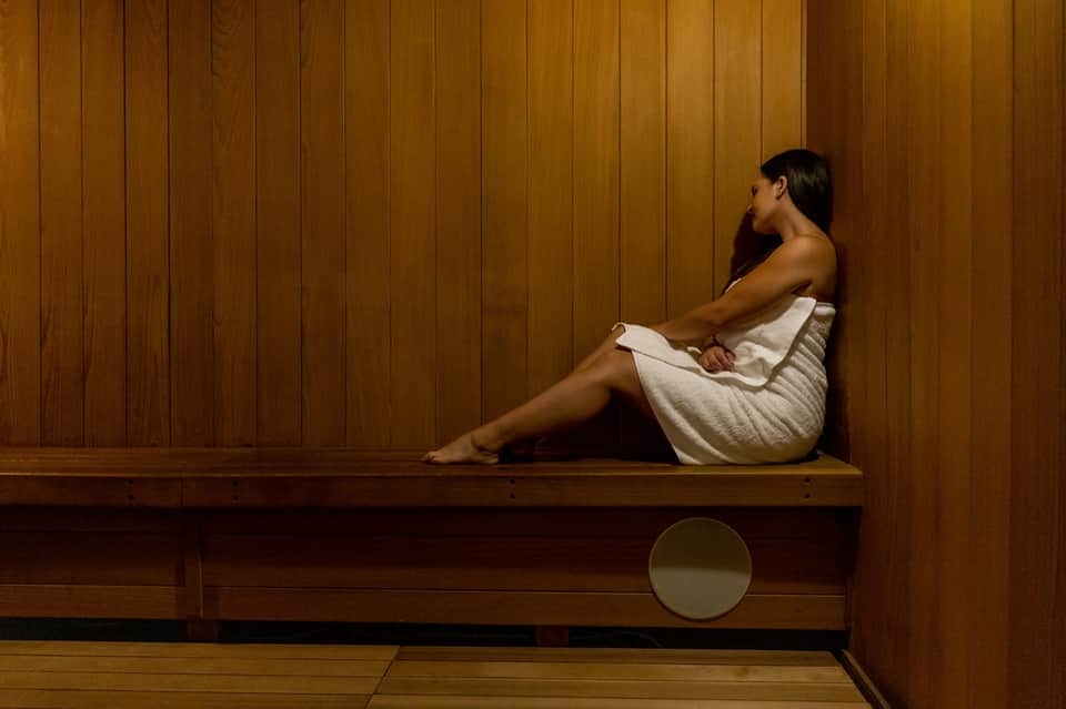 Woman relaxing in wooden sauna interior with paneled walls