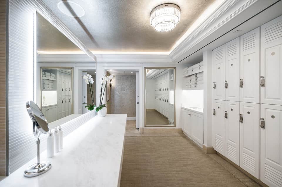 Spa locker room with white lockers, vanity mirror, and marble counter