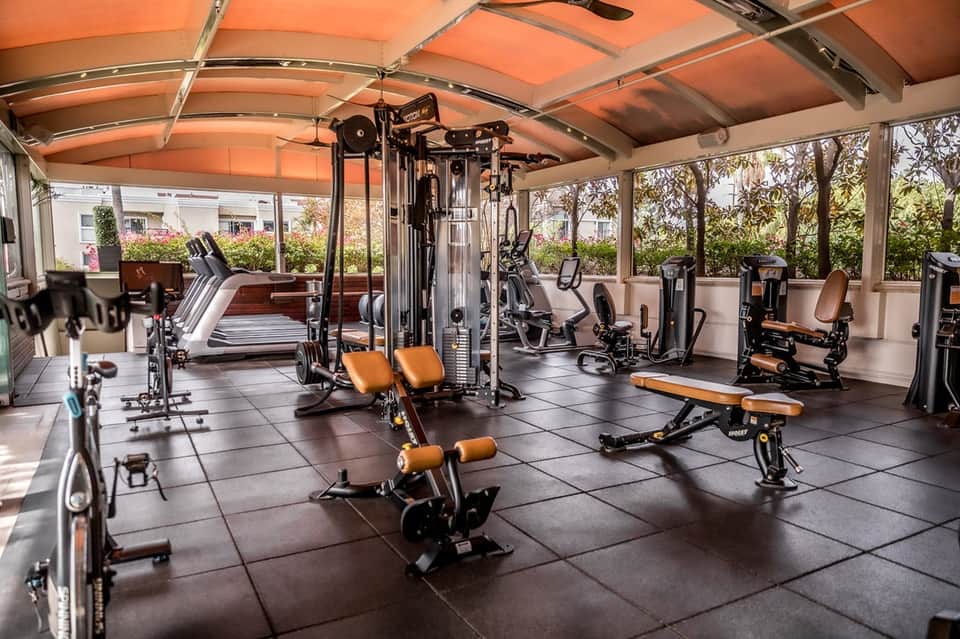 Indoor fitness center with orange ceiling, exercise equipment, and treadmills