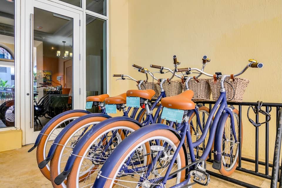 Row of blue and orange bicycles parked on yellow residential building with white doors